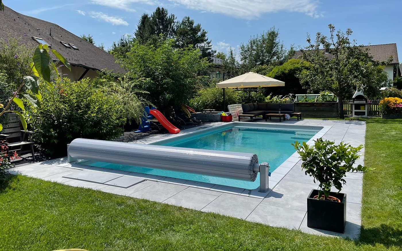 Pool vom Poolbau Gollner mit Liegest&uuml;hlen und Sonnenschirm vor Bergkulisse