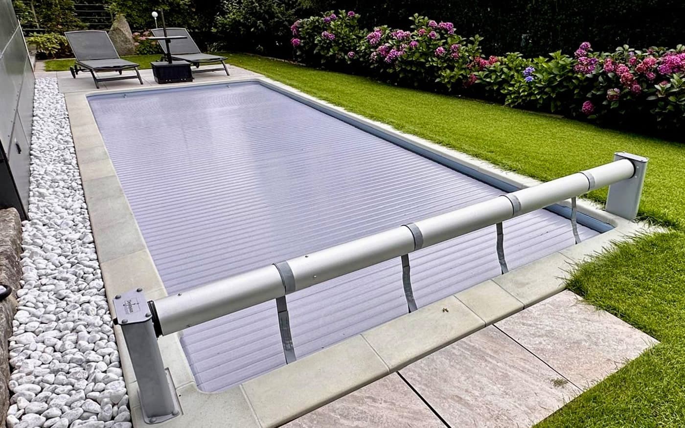 Abgedeckter Pool Desjoyaux im Garten mit zwei Liegest&uuml;hlen daneben