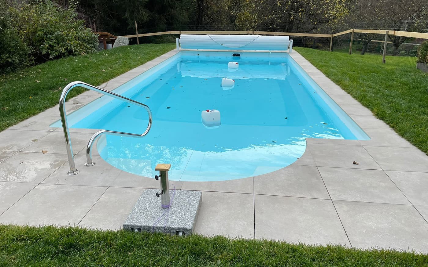 Rechteckiges Schwimmbecken Desjoyaux im Garten mit blauer Wasseroberfl&auml;che und flachem Handlauf