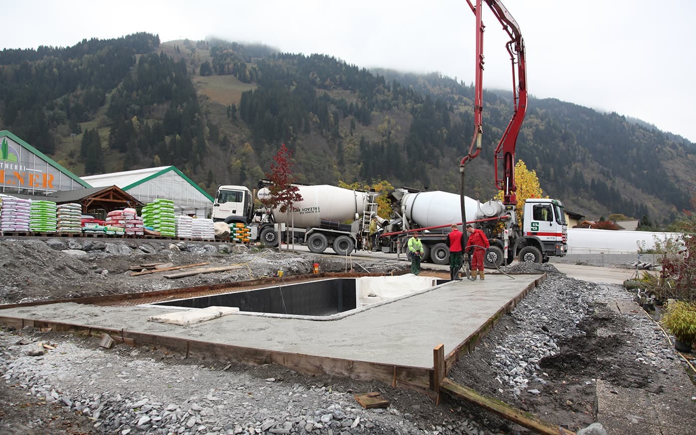 Bauarbeiter betonieren eine Fl&auml;che auf einer Baustelle in einer bergigen Umgebung