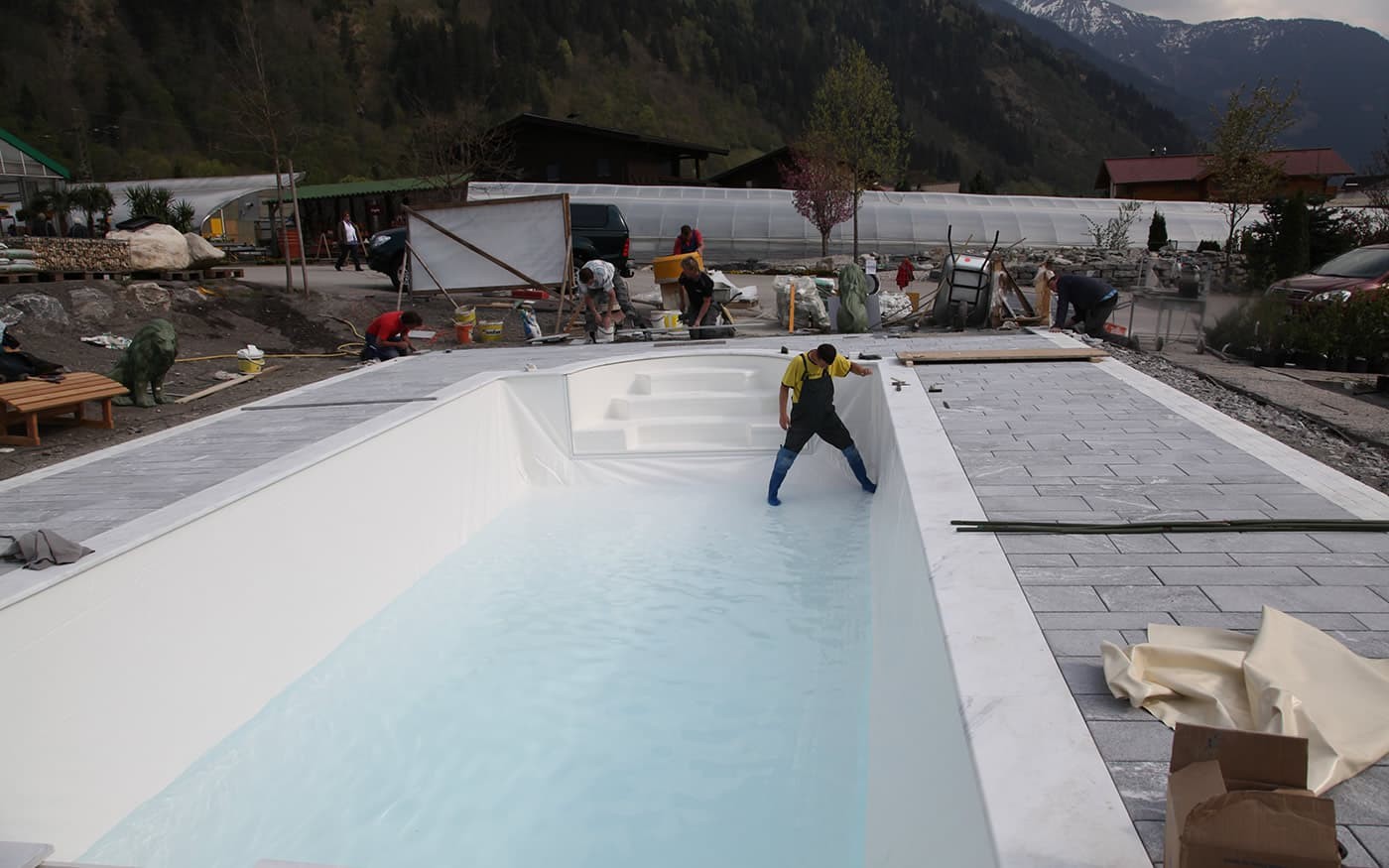 Ein Arbeiter richtet einen teilweise gef&uuml;llten Pool auf einer Bergbaustelle aus