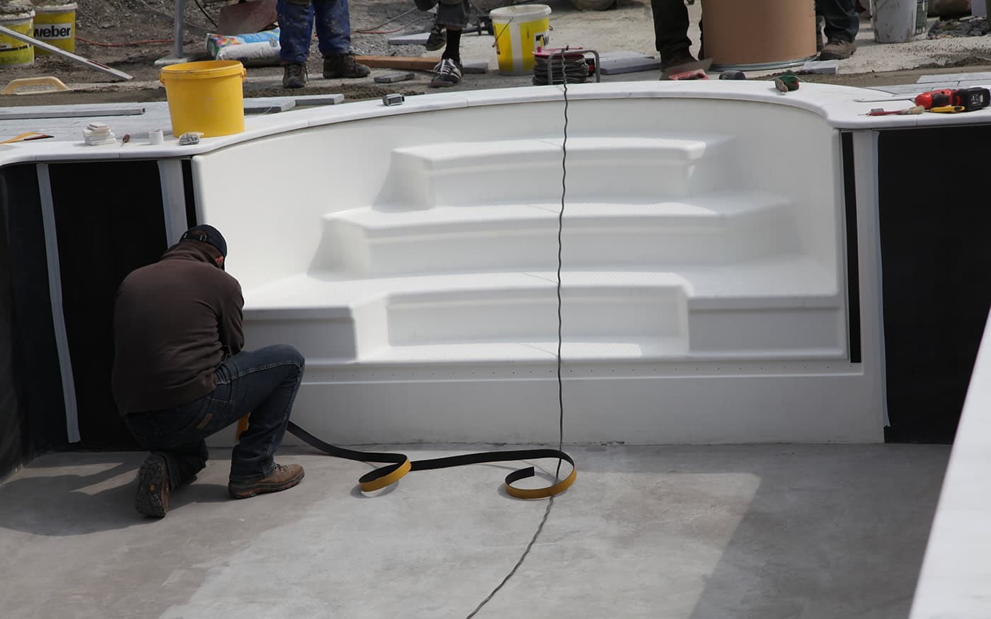 Ein Arbeiter installiert eine wei&szlig;e Treppe in einem halbfertigen Bauprojekt