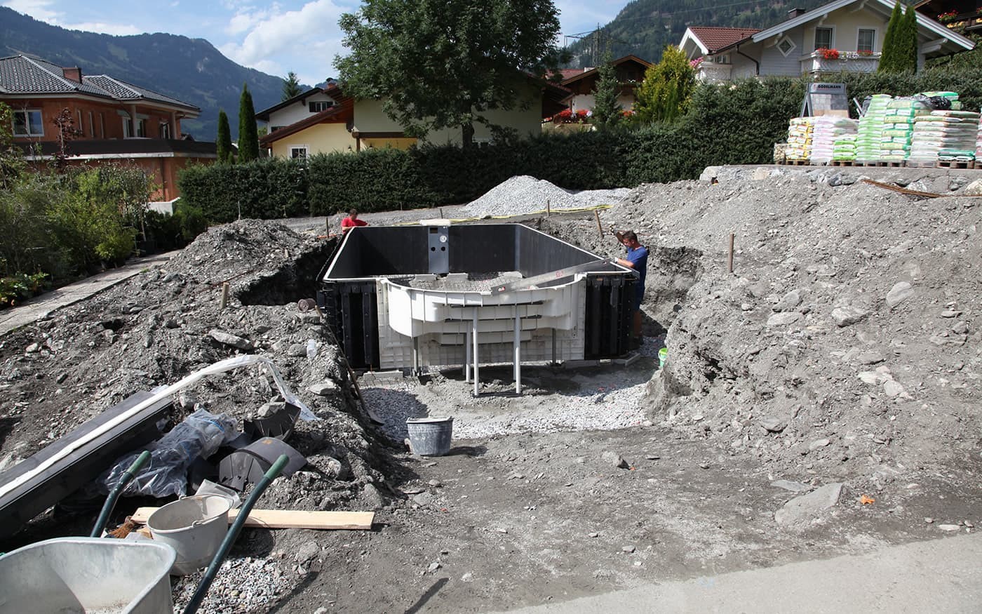 Baustelle mit teilweise installiertem Betonbeh&auml;lter und Materialien im Hintergrund