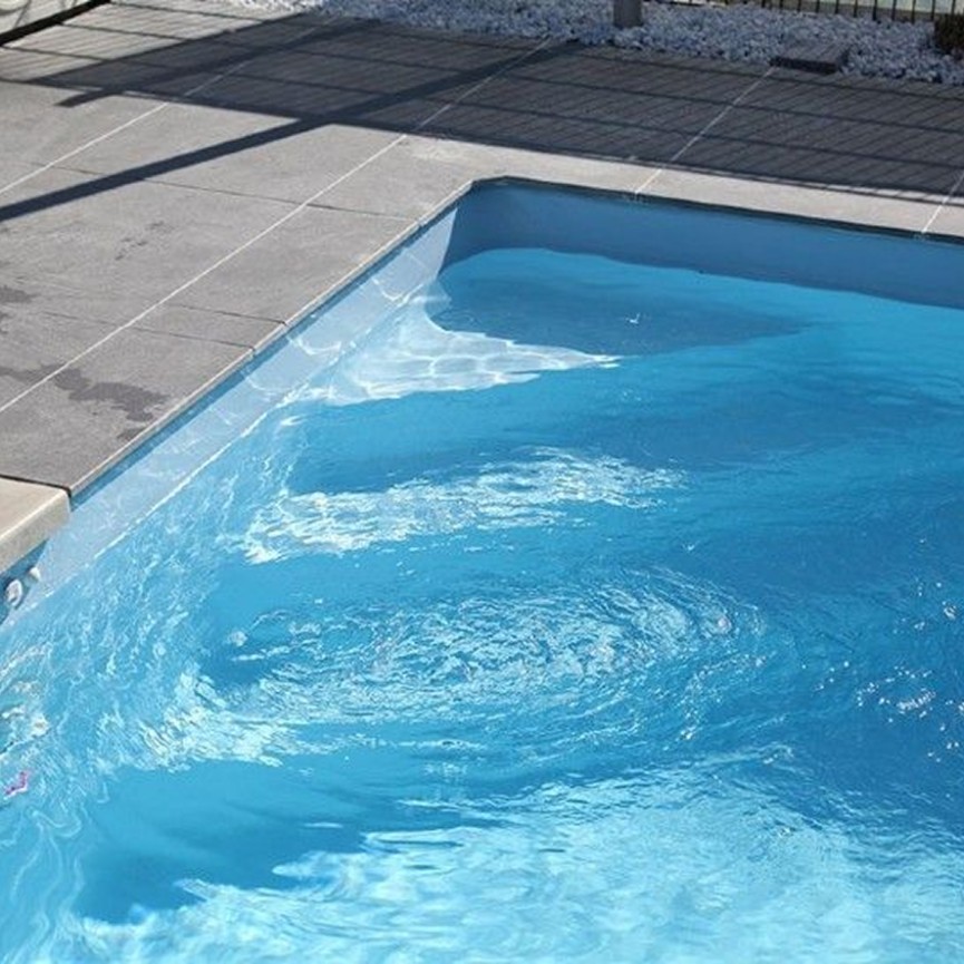 Ein kleiner blauer Pool Desjoyaux mit leichten Wasserbewegungen bei Sonnenschein