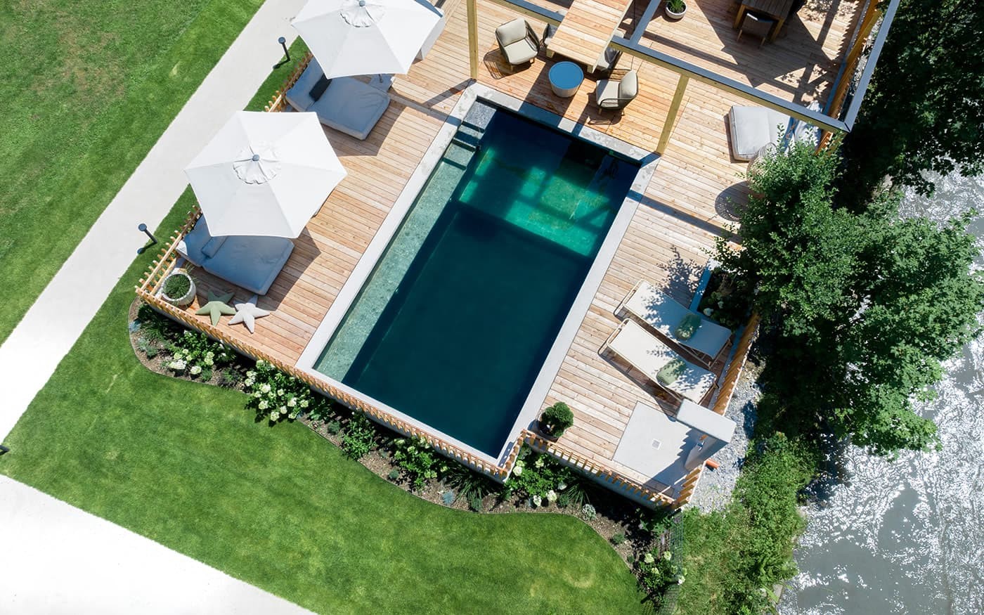 Ein moderner Pool mit Holzterrasse, Liegest&uuml;hlen und Pflanzen von oben gesehen