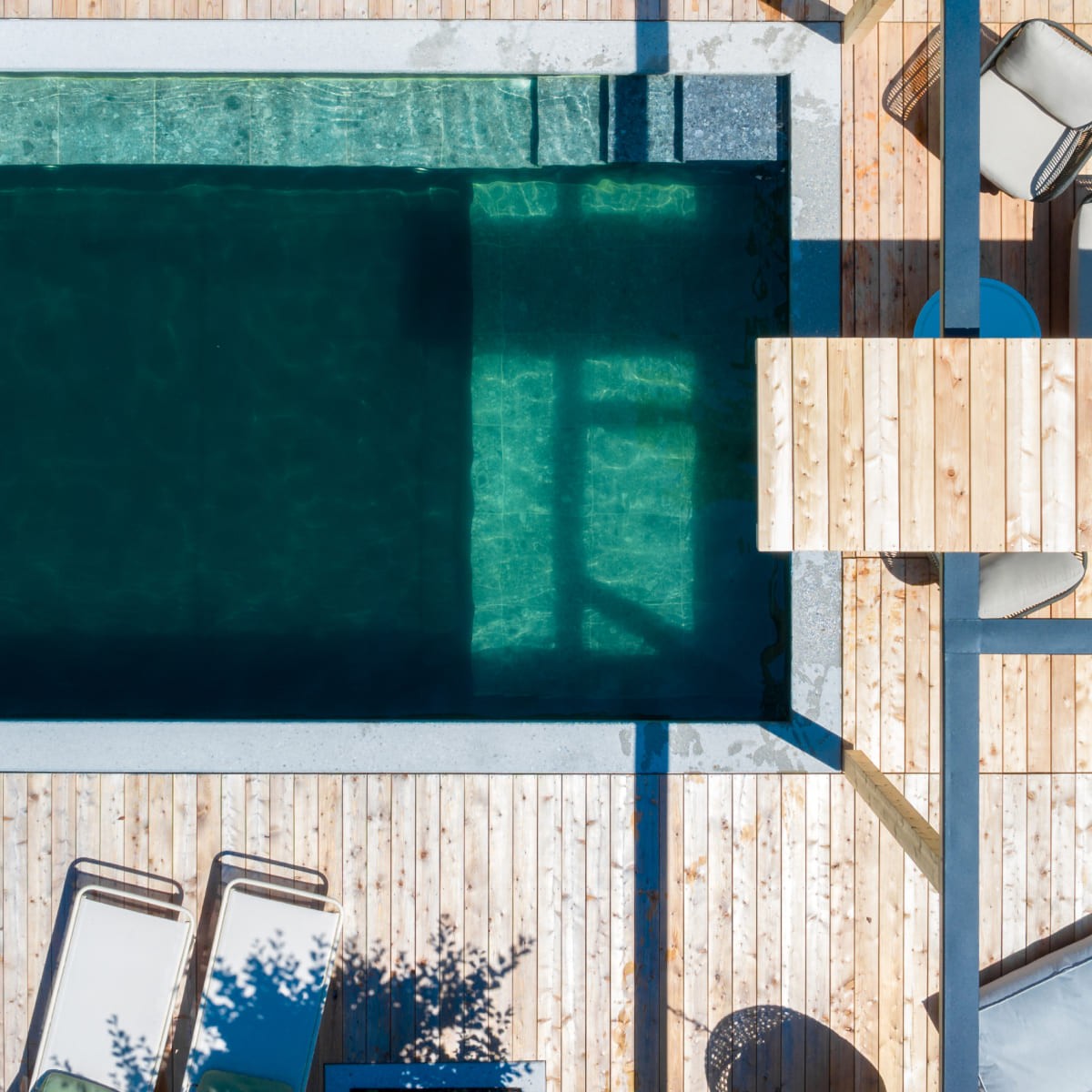 Vogelperspektive auf einen Pool mit Holzterrasse und Liegest&uuml;hlen