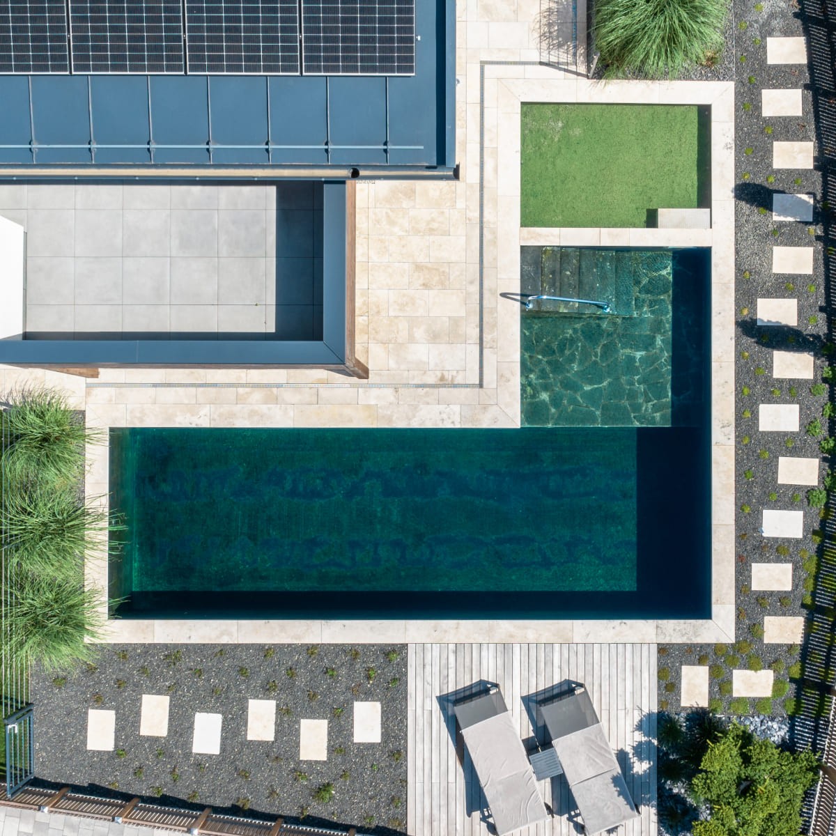 Luftaufnahme eines modernen Pools mit umliegender Terrasse und Solarpanel