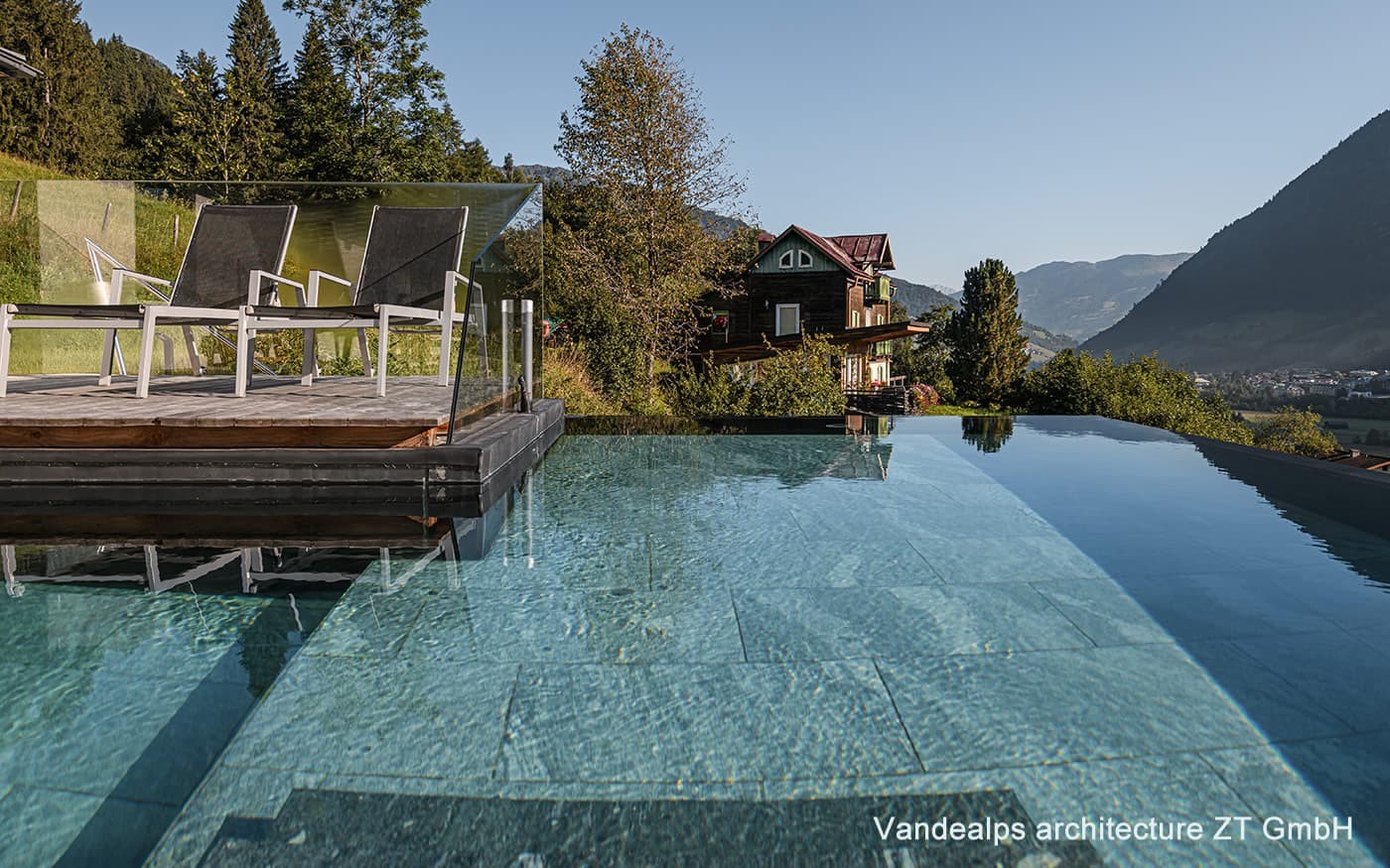 Ein Infinity-Pool mit Liegest&uuml;hlen und Bergblick bei klarer Himmel
