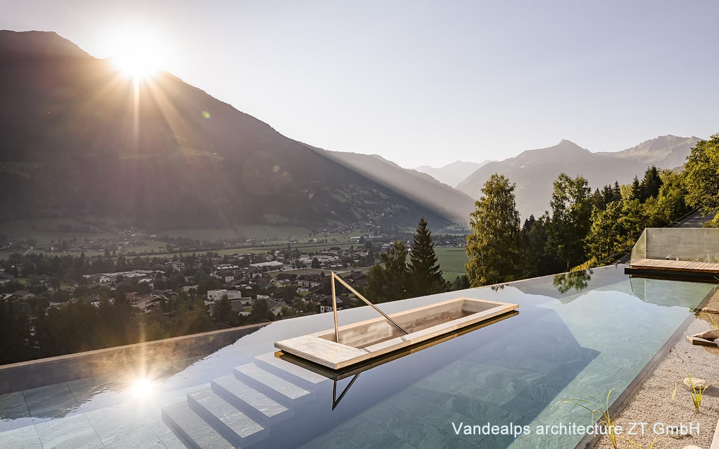 Infinity-Pool mit Blick auf ein Tal und Berge bei Sonnenaufgang