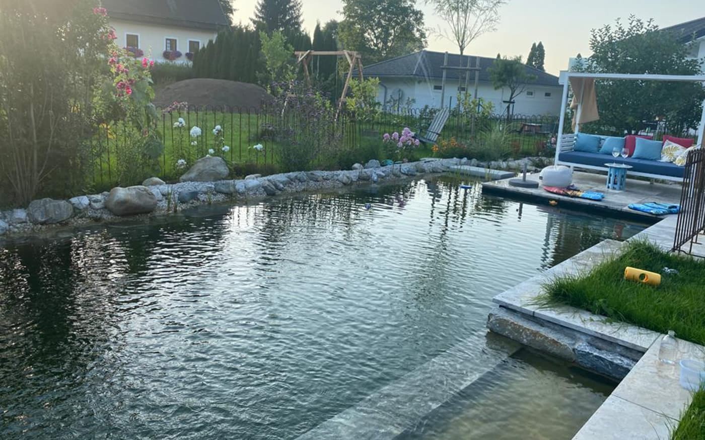 Garten mit Naturteich, Sitzbereich und bl&uuml;henden Pflanzen ringsum